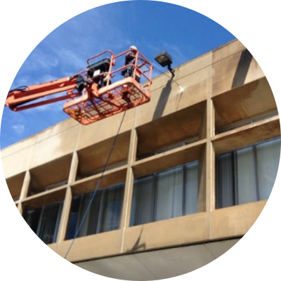 2 workers pressure washing the exterior of commercial building